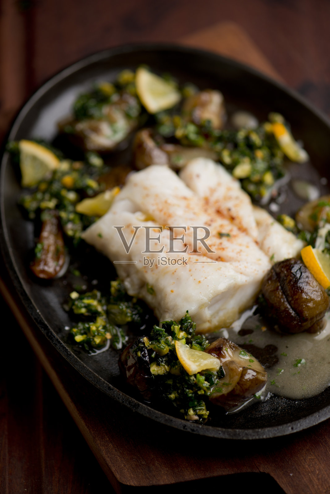 比目鱼片烤盘，用卡真调味和新鲜香草。搭配有机蒸蔬菜，青椒，南瓜，胡萝卜和西葫芦。经典的美国或法国小酒馆的主菜。盛在铸铁煎锅中。照片摄影图片