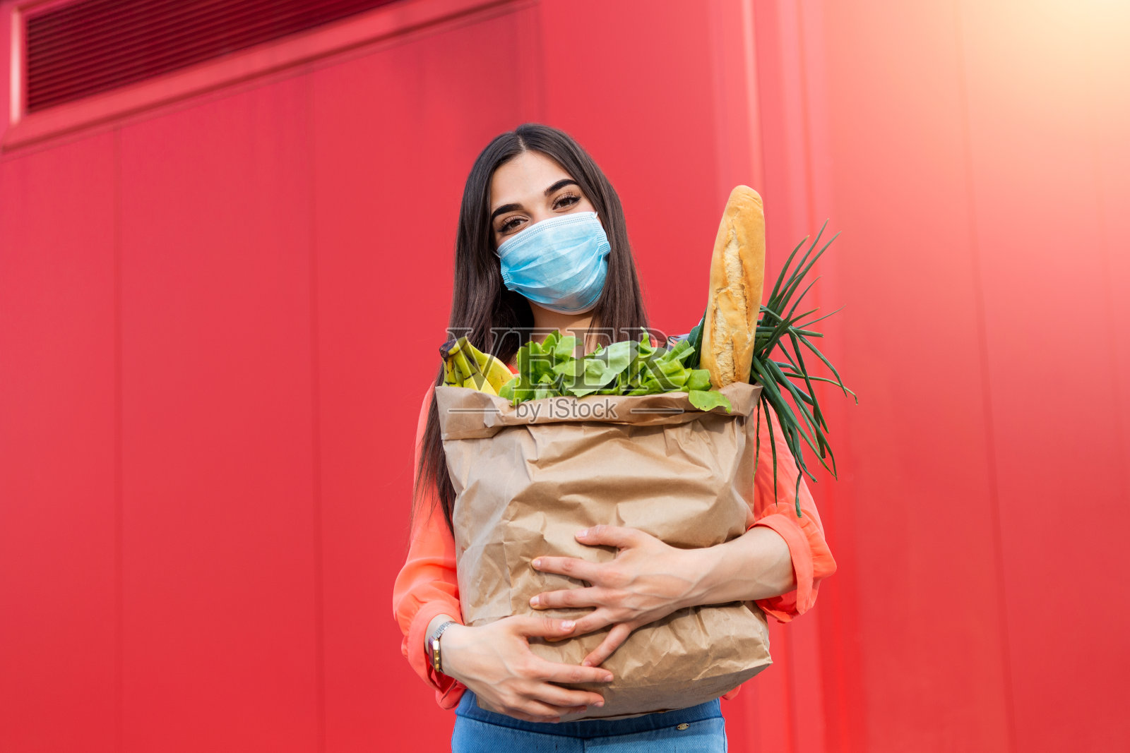 买家戴着防护面具。新冠肺炎疫情期间购物、冠状病毒大流行检疫。戴着医用口罩的妇女手持一个装有食物、水果和蔬菜的纸袋照片摄影图片
