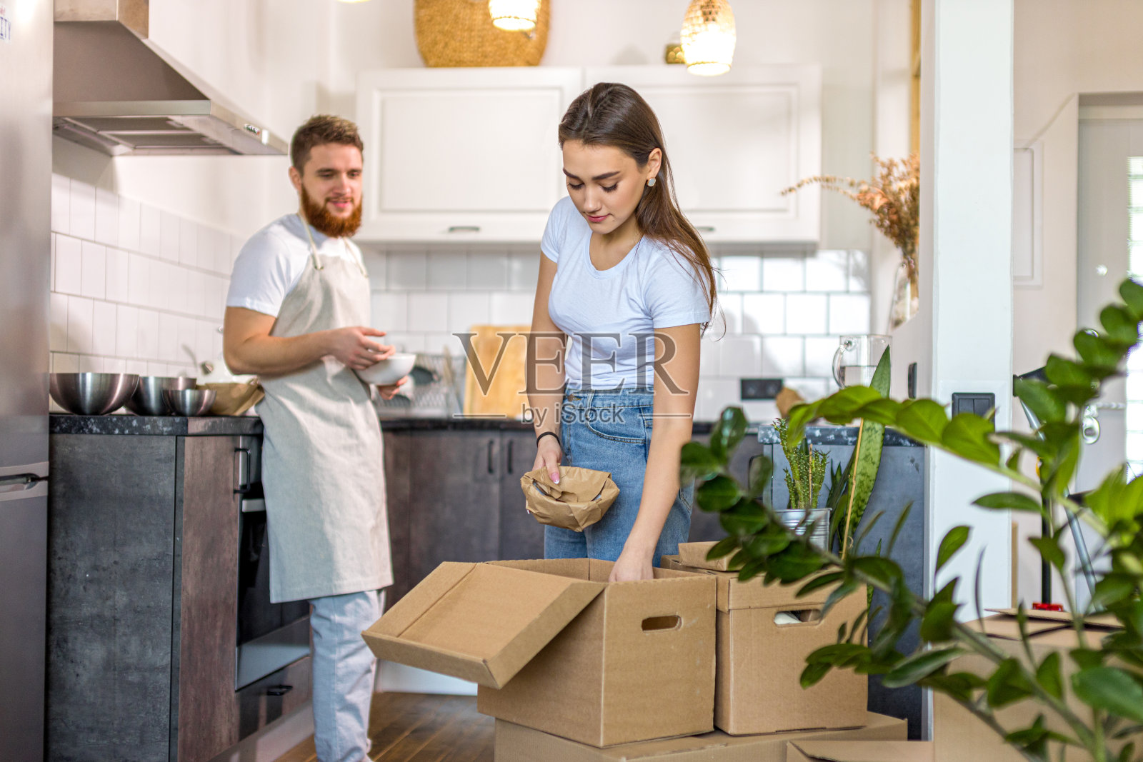 年轻幸福的夫妇在搬到新房子后打开纸箱照片摄影图片