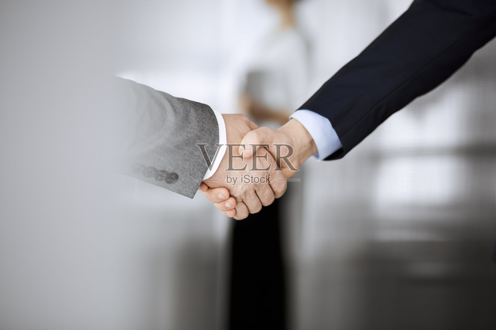 商务人士穿着西装站着握手，特写。商务沟通的概念。握手和营销照片摄影图片