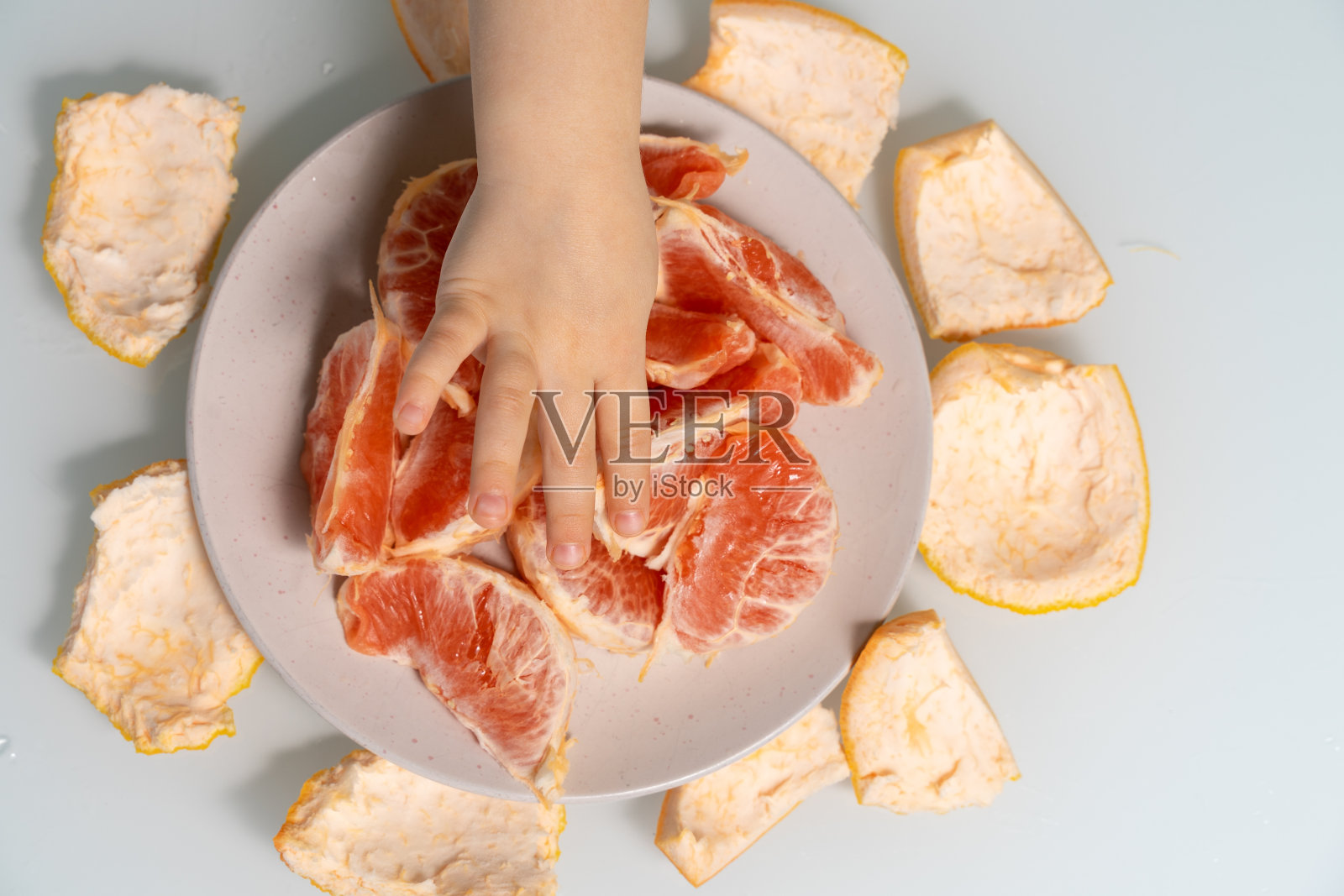 葡萄柚片放在盘子里，孩子们的手照片摄影图片