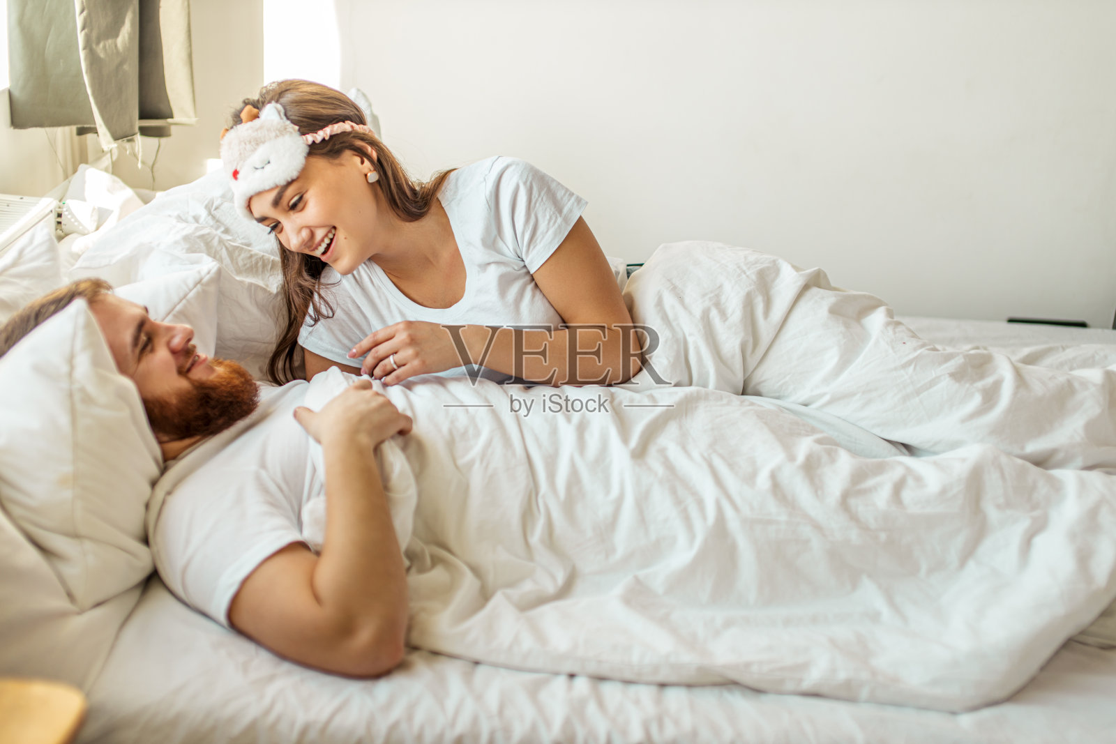 一对年轻的夫妇早晨躺在床上照片摄影图片