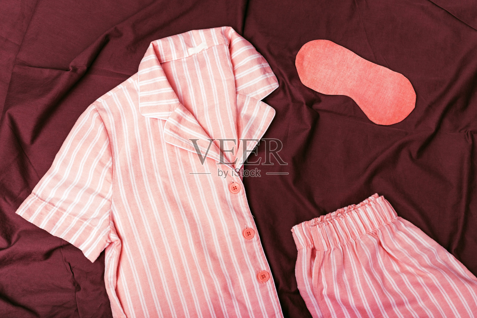 温暖的粉红色睡袋。柔软的棉质t恤和短裤。舒适的衣服，健康的睡眠。睡衣在床上整齐复杂。前视图。平的。照片摄影图片