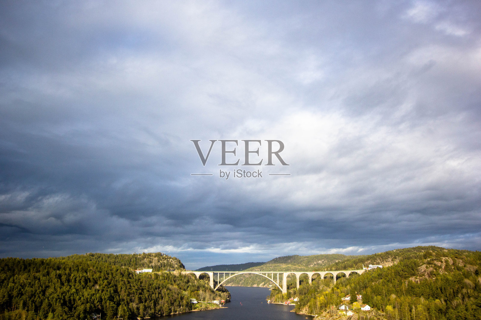 缓慢的河流，周围有引人注目的云彩和树木照片摄影图片