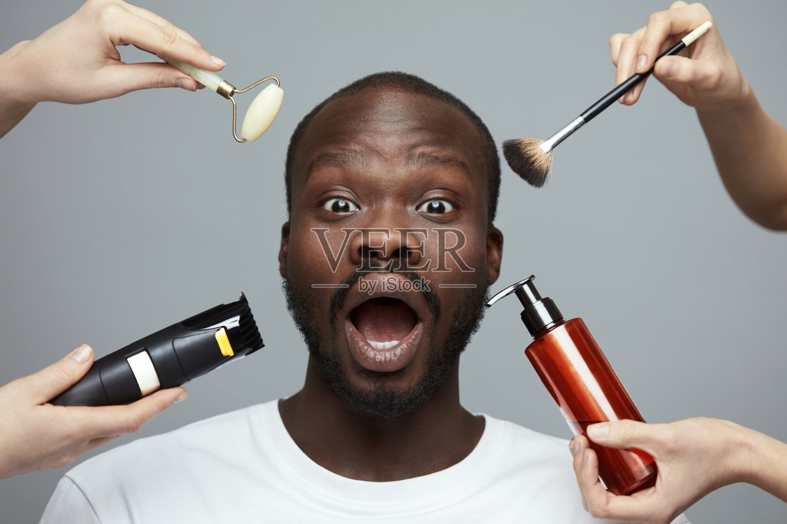 男性的皮肤护理。非洲模特面部美容治疗。玉辊，电动剃须刀，化妆刷和液体在男人的脸附近。照片摄影图片