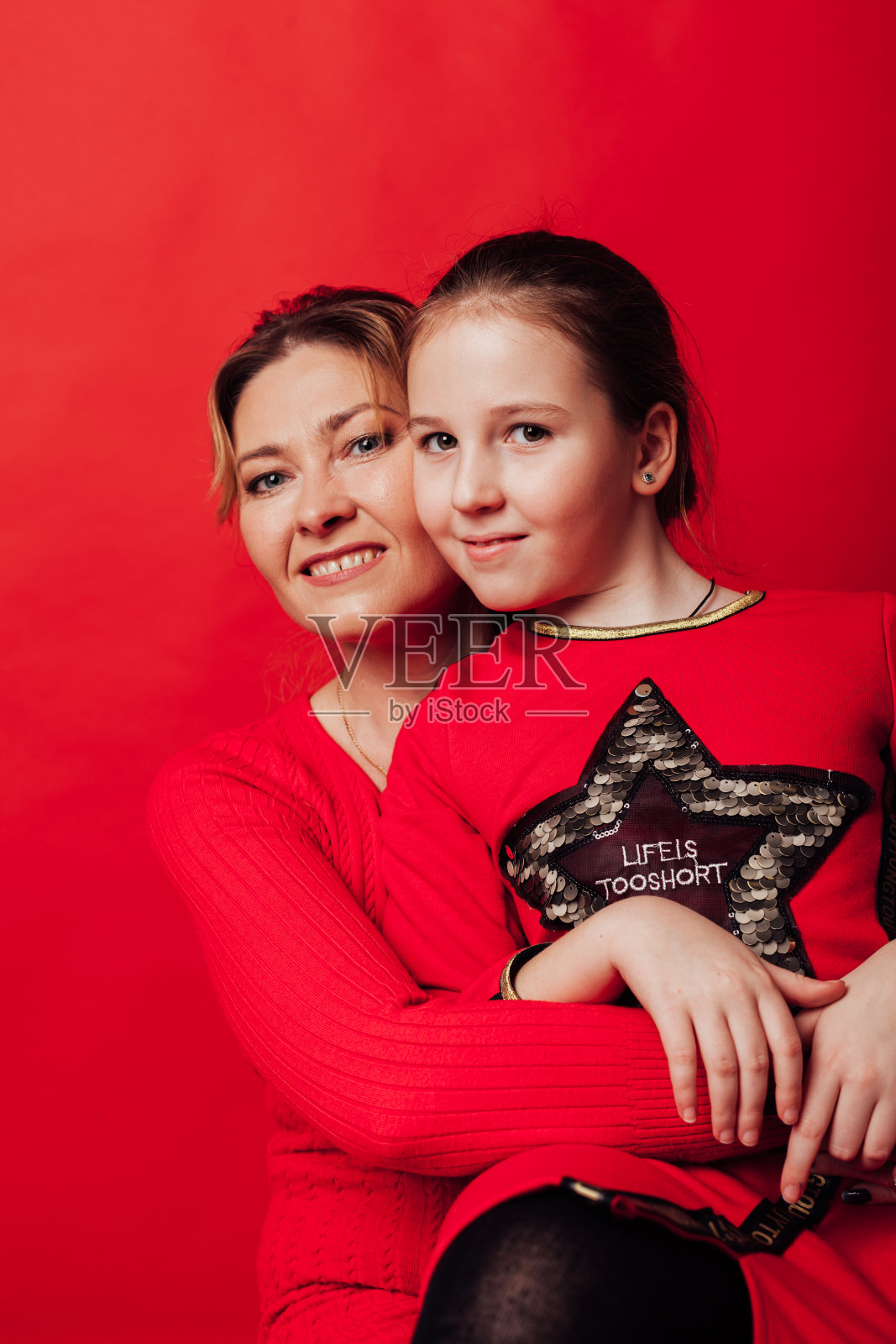 妈妈和女儿可爱地拥抱在一个红色的背景照片摄影图片