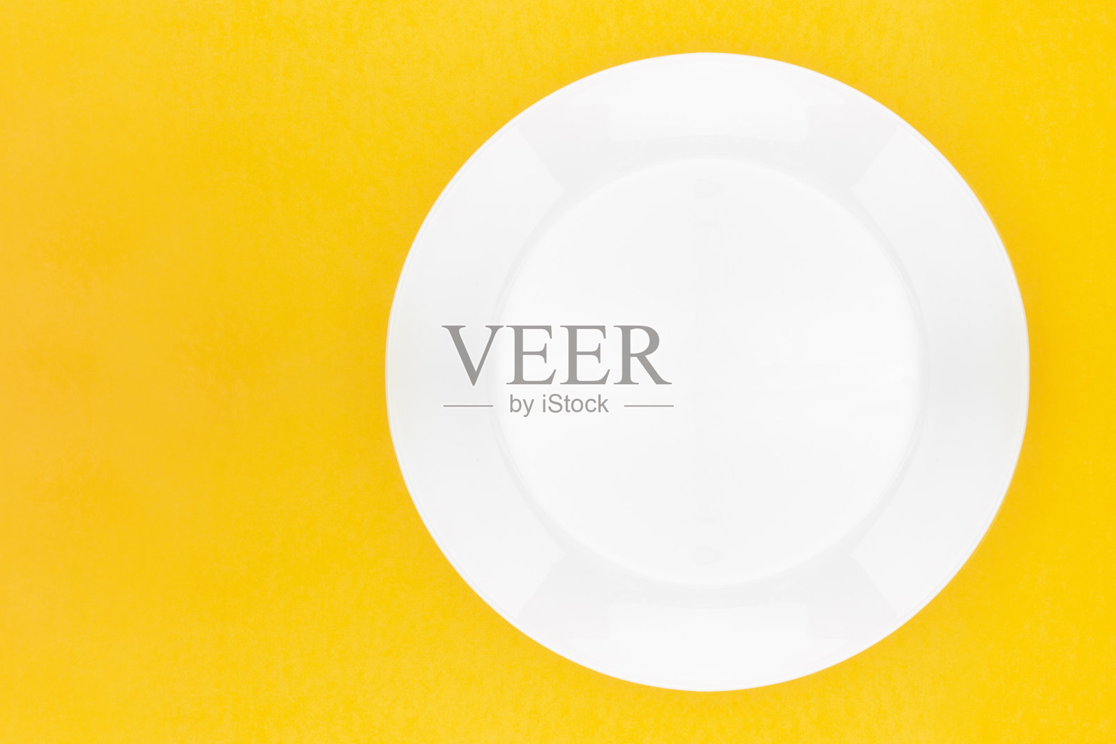 黄色背景上的空白白色餐盘。前视图。空白的设计与复制空间。照片摄影图片