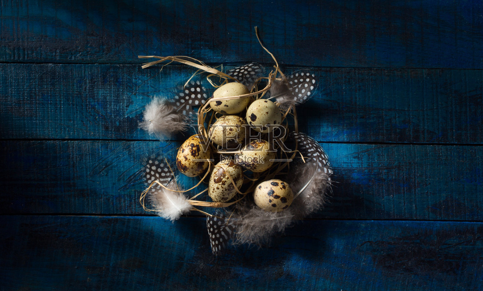 有机复活节彩蛋和羽毛在蓝色木制背景照片摄影图片