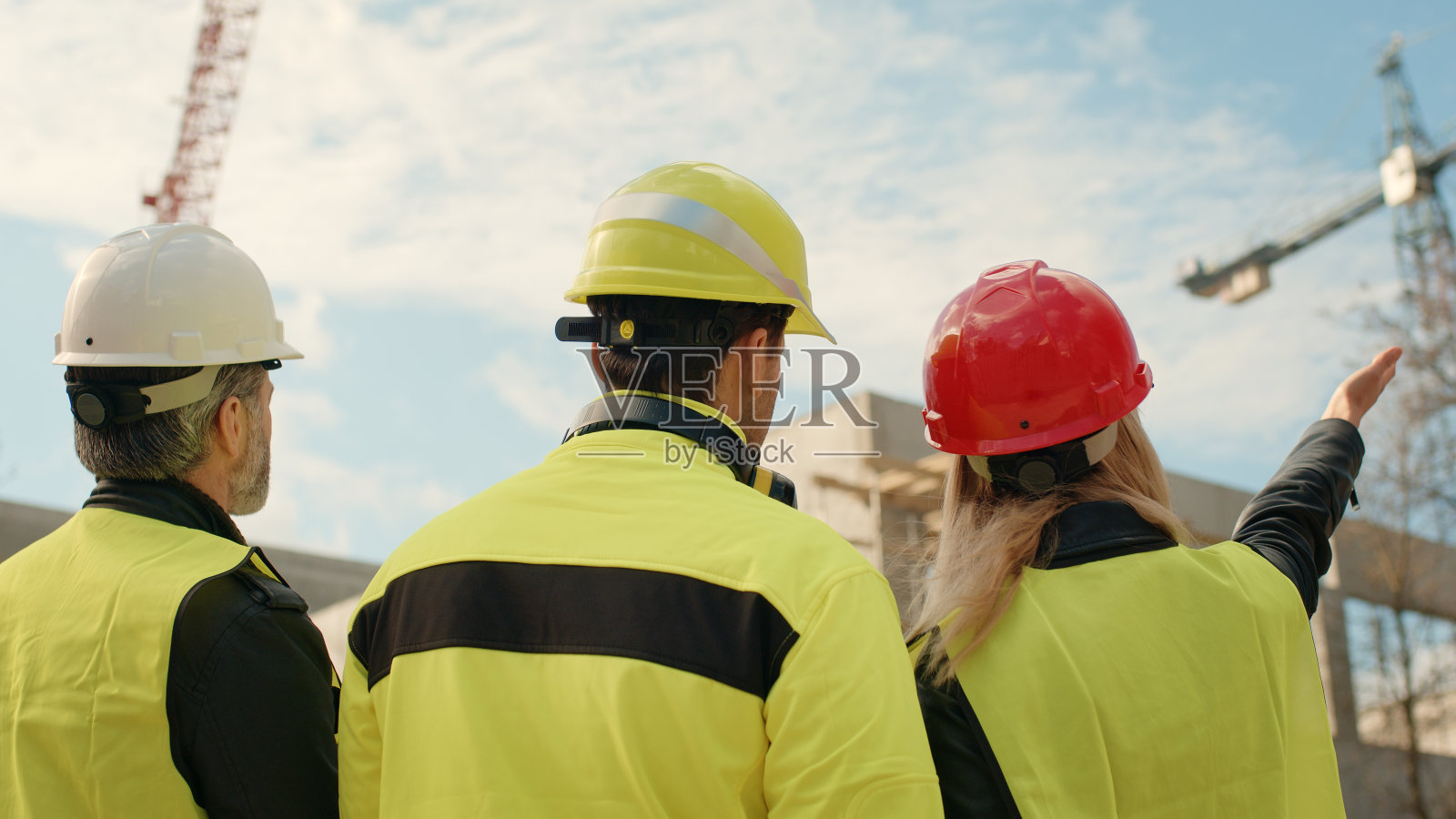 建筑工地上的建筑工程师，后视图，指向起重机照片摄影图片