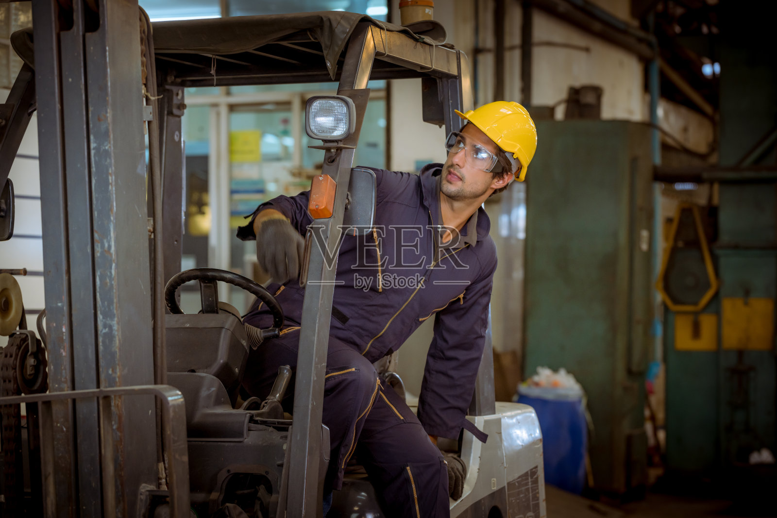 肖像工人工业工厂穿安全制服工厂驾驶叉车和开车灯控制另一工人在工厂区域的生产工作。照片摄影图片