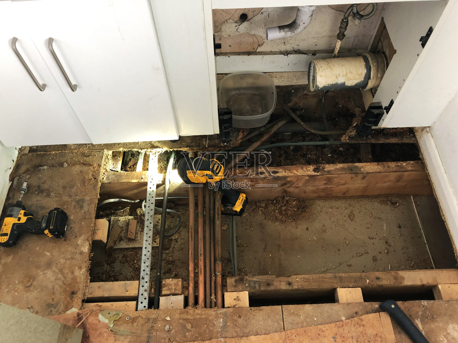 水损坏的浴室刨花板地板，漏水孔，铜管和连接器，中央供暖系统，住房问题概念照片摄影图片