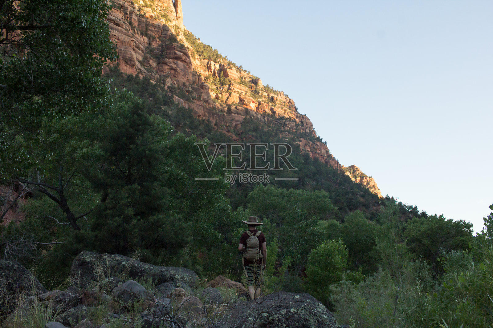 夕阳照耀在犹他州锡安国家公园的山脊上，一名男子走在前景中照片摄影图片