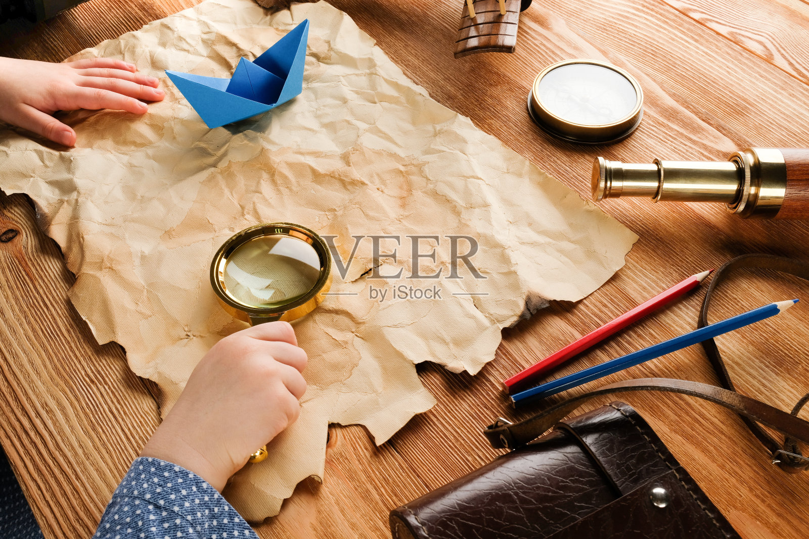 地图，放大镜和指南针放在桌子上。一个孩子扮演一个旅行者。冒险和旅行的概念。照片摄影图片