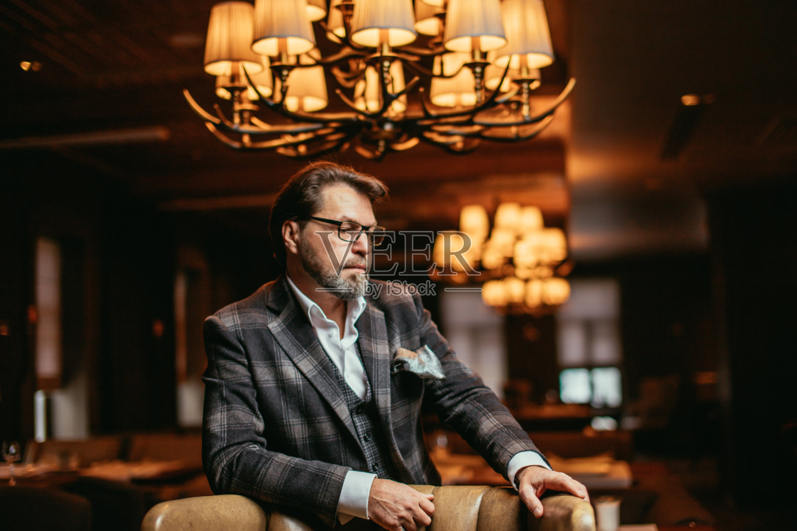 大胡子商人坐在皮椅上思考重要。照片摄影图片