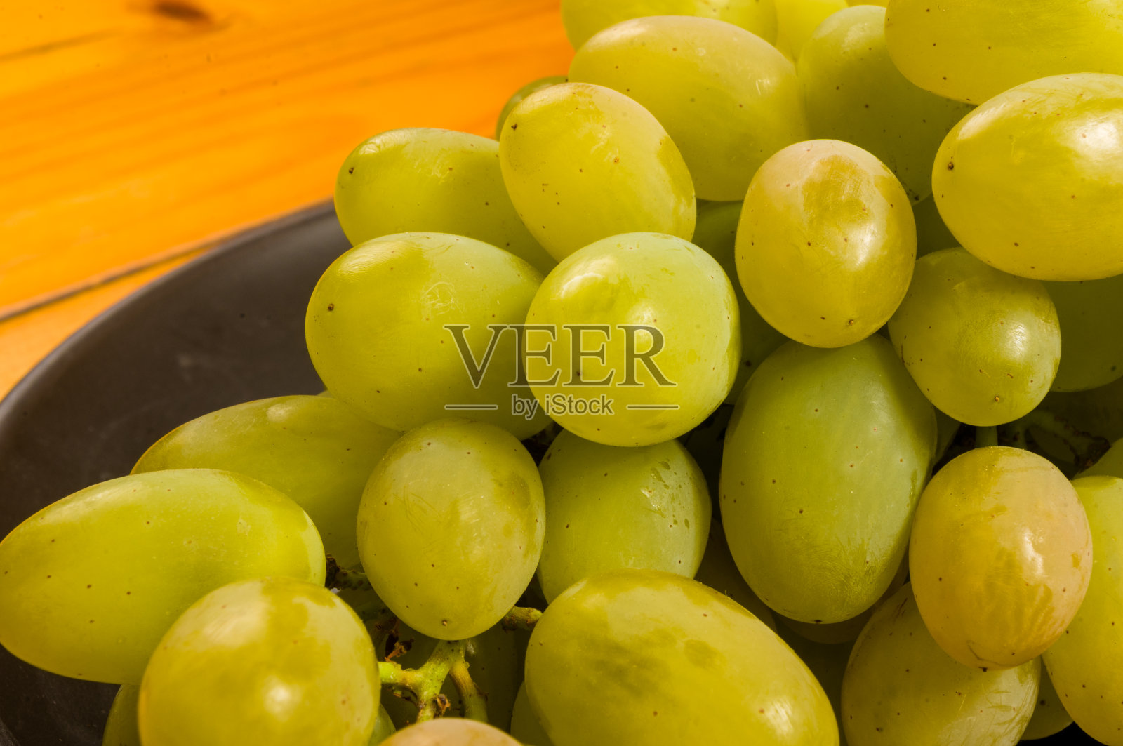 大刷子绿色葡萄在一个深色陶瓷盘子在木制的背景照片摄影图片