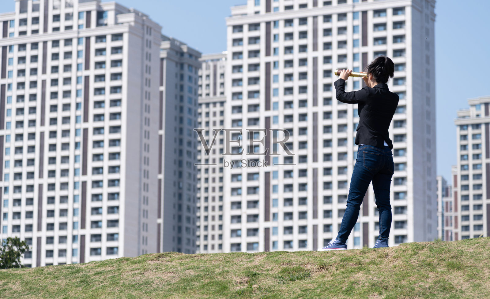 透过望远镜看外面的女商人照片摄影图片