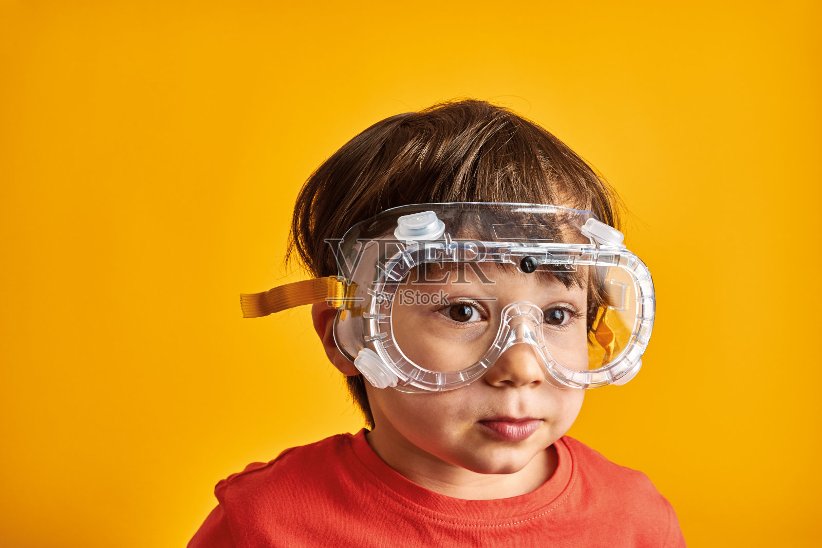 黄色背景的孩子戴着防护眼镜。照片摄影图片