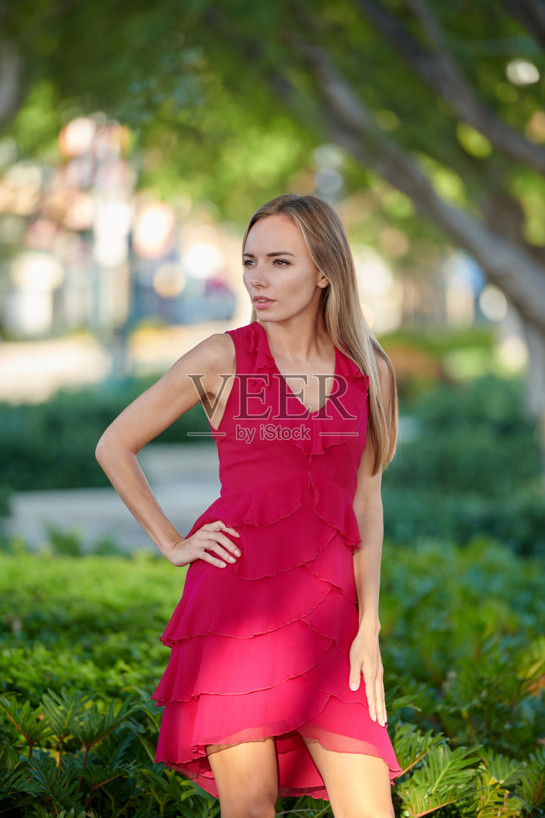 金发女人穿着红色的裙子在街道的背景看过肩膀照片摄影图片