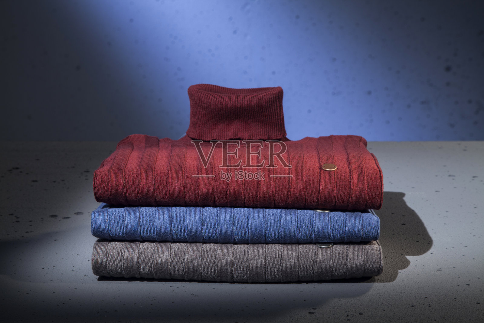 折叠的男毛衣孤立在蓝色背景上。照片摄影图片