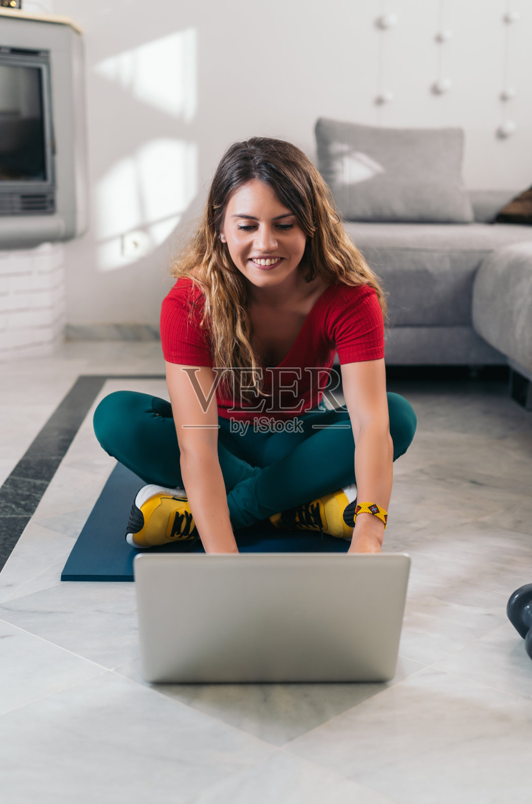 在家用笔记本电脑上在线课程后，一个女人在垫子上做运动照片摄影图片
