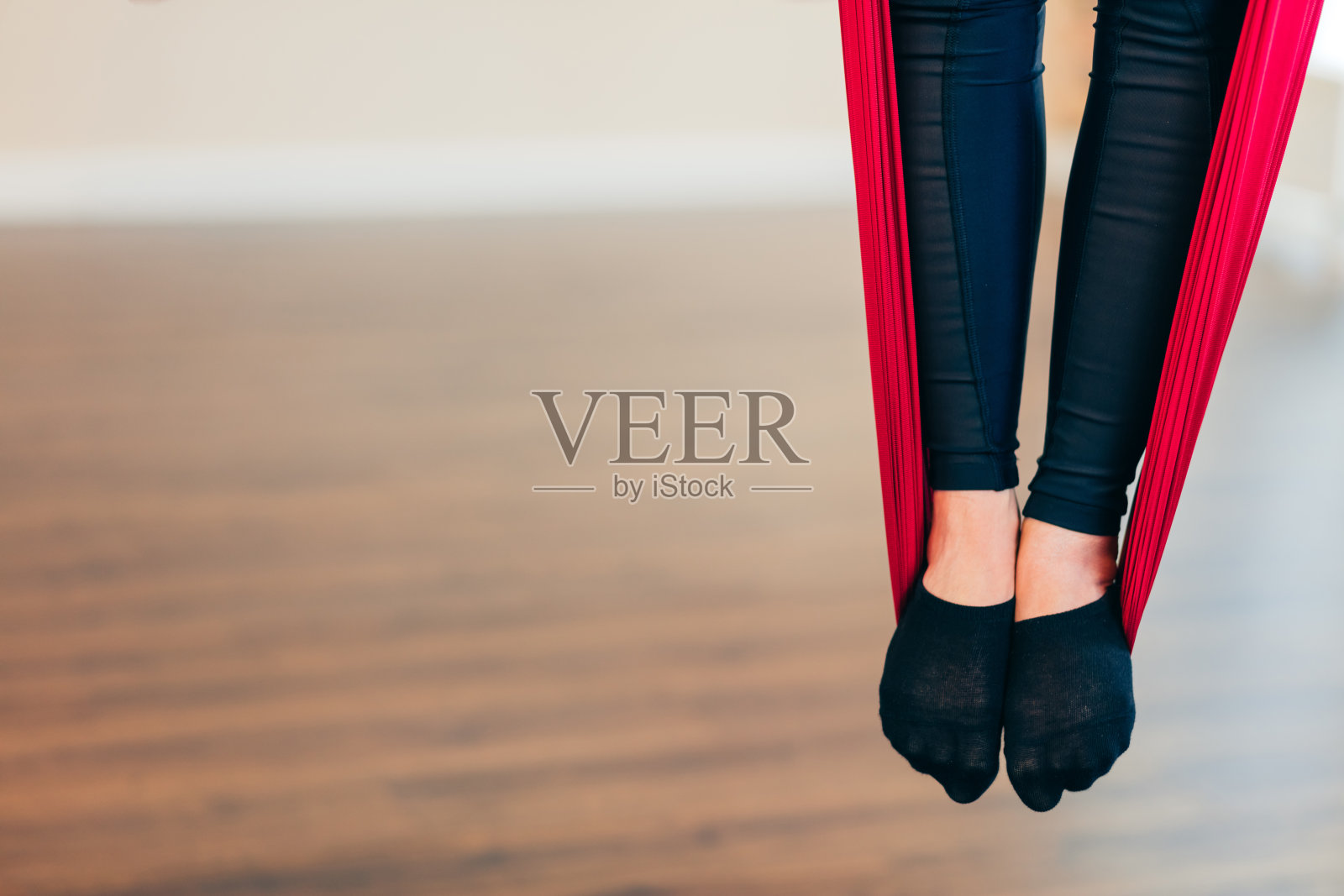 在空中瑜伽课上，女性的腿在红色吊床上，特写。照片摄影图片