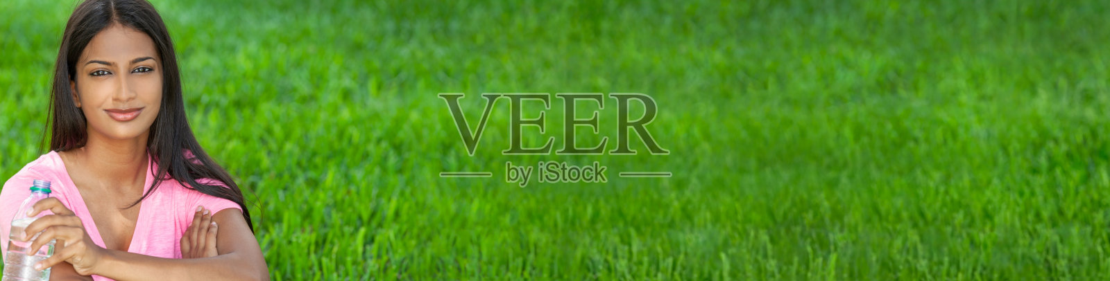 全景户外肖像一个美丽的快乐的印度亚洲年轻女子或女孩在夏天的阳光下饮用一瓶水。全景网络横幅。照片摄影图片