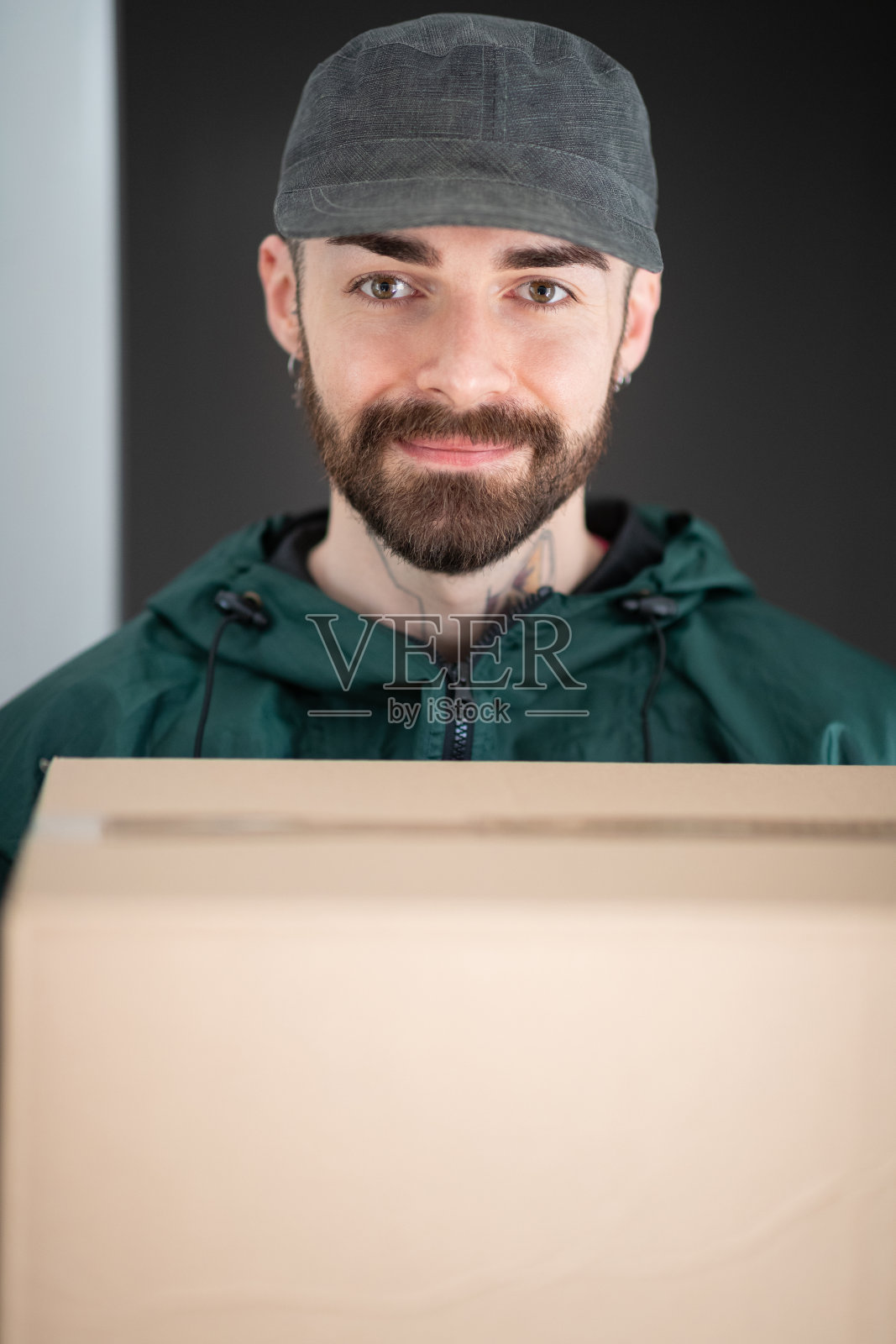 快递员戴着帽子带着快递包裹进入公寓照片摄影图片