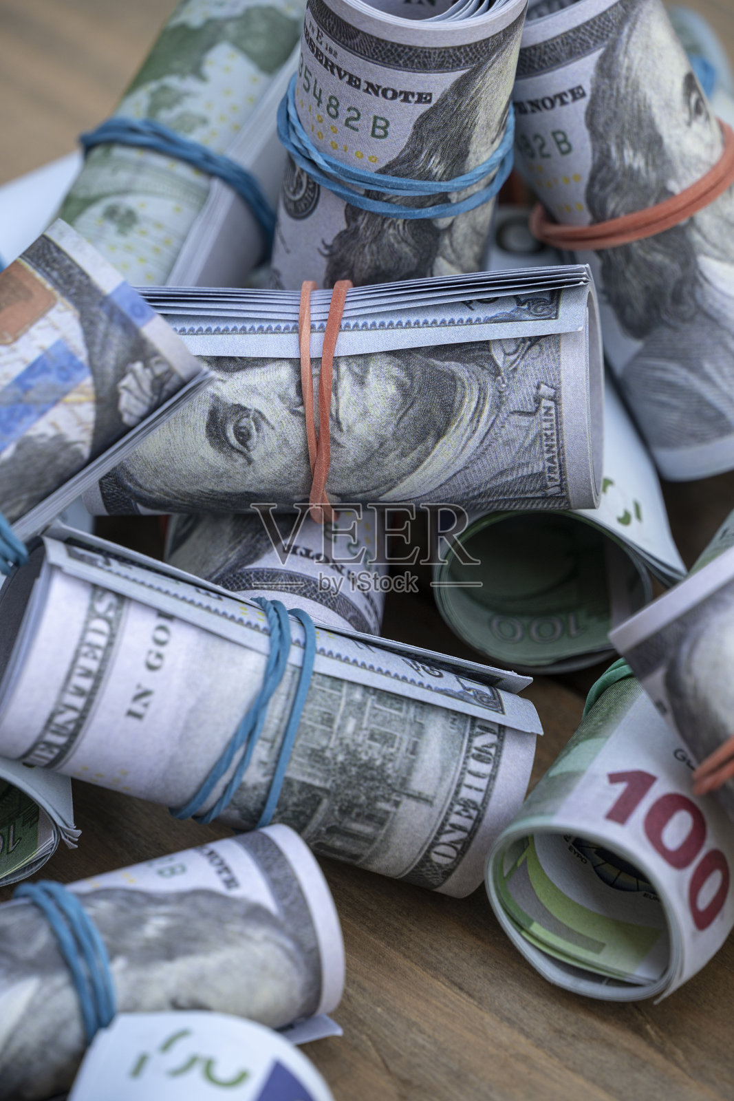 花园桌上一卷一百美元和欧元的钞票。照片摄影图片