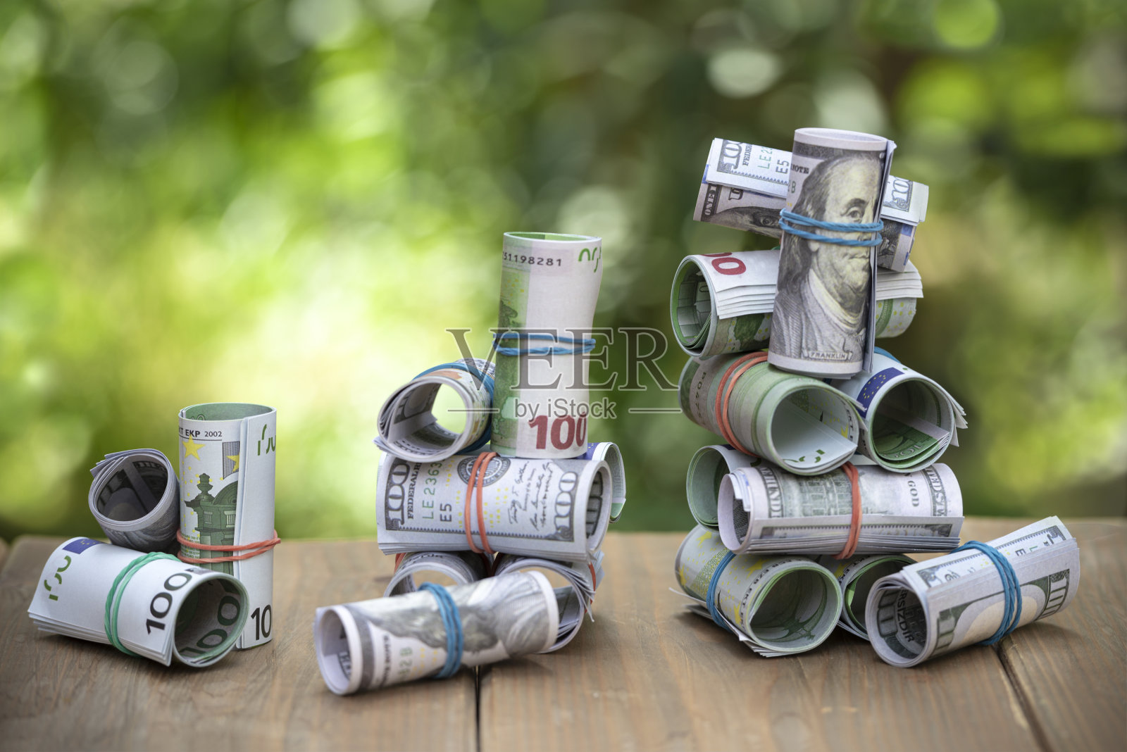 花园桌上一卷一百美元和欧元的钞票。照片摄影图片