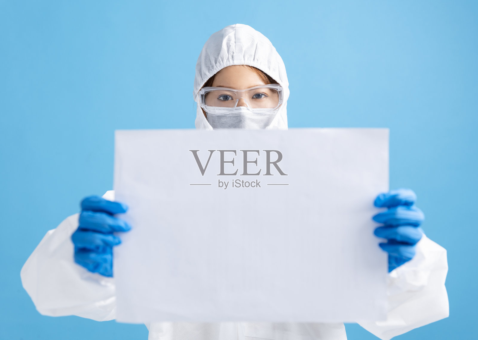 女护士戴医用口罩，戴安全眼镜，穿白色防护服。显示空白的广告牌照片摄影图片