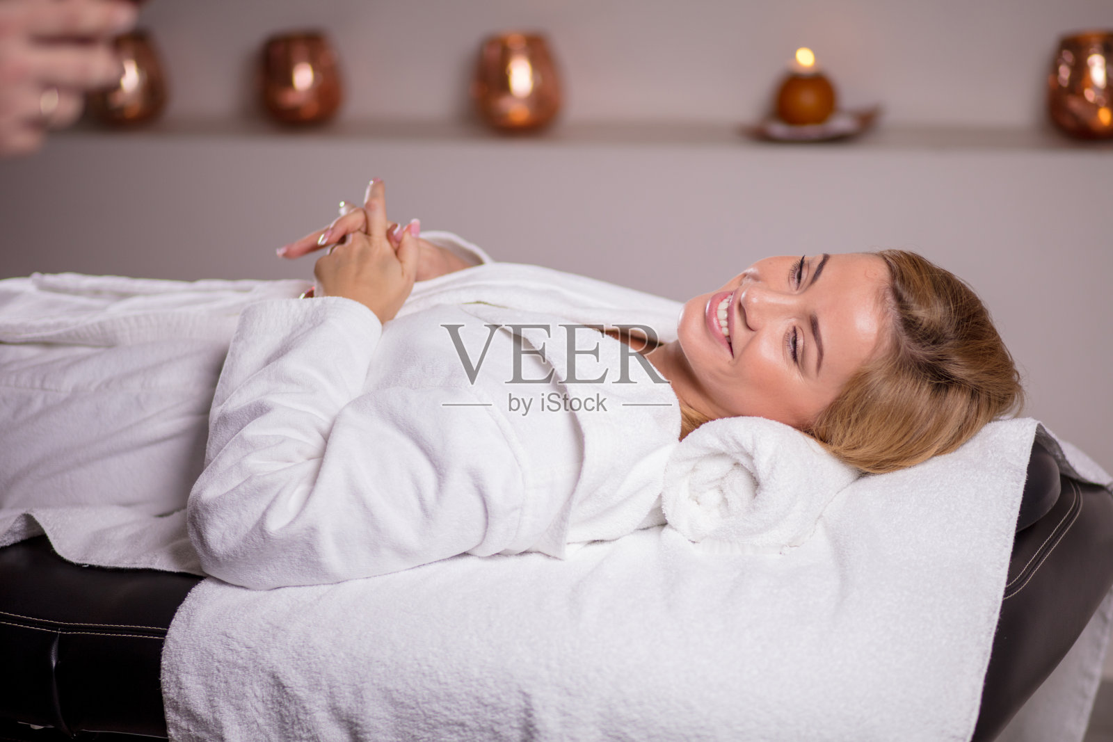 迷人的快乐女孩在白色浴衣放松水疗沙龙。照片摄影图片