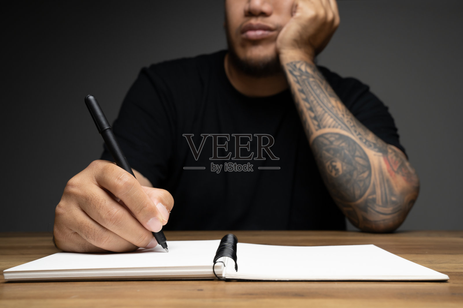 一个亚洲人在木制桌子上写着一张无聊的脸。远程工作的概念。照片摄影图片