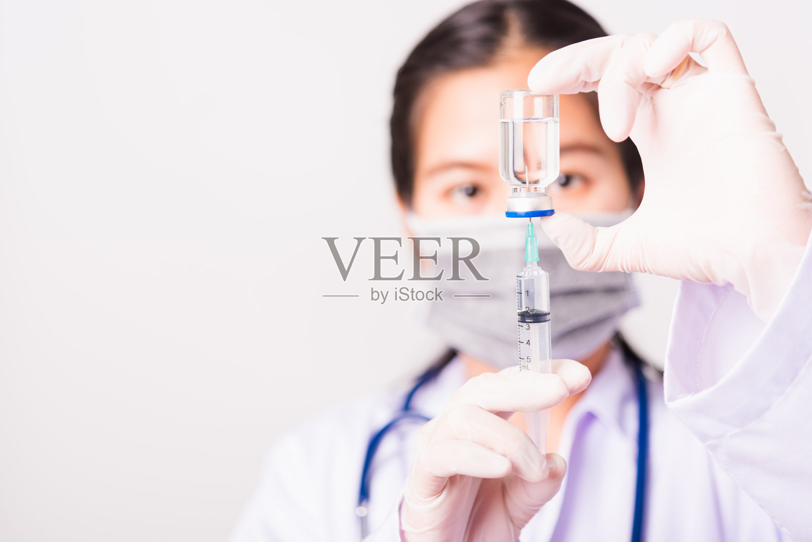 亚洲女医生或女护士穿着制服，戴着手套，戴着听诊器面罩，在实验室里拿着注射器和药瓶小瓶疫苗，健康医学观念照片摄影图片