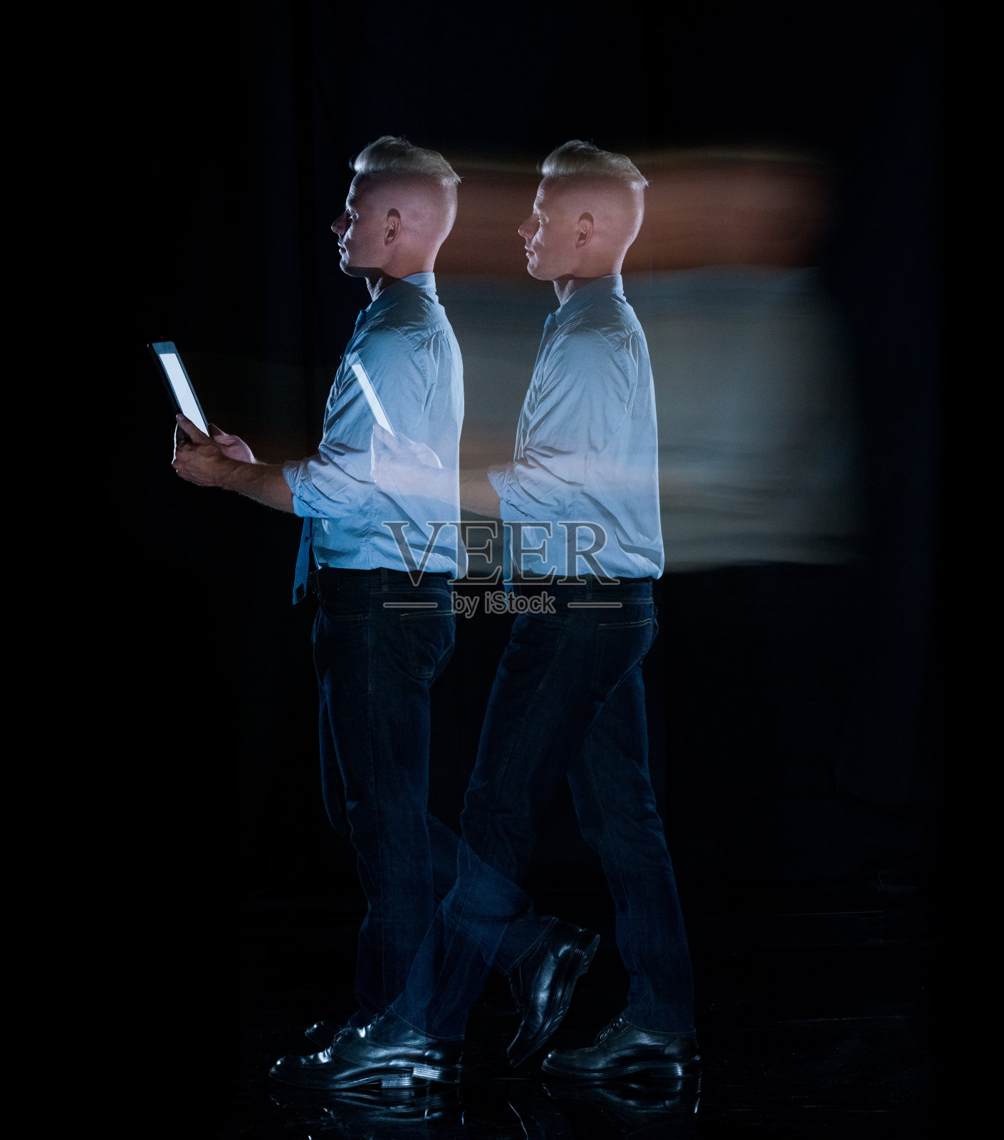 白人男性商务人士长时间暴露在黑色背景前，穿着商务休闲装，使用数码平板电脑照片摄影图片