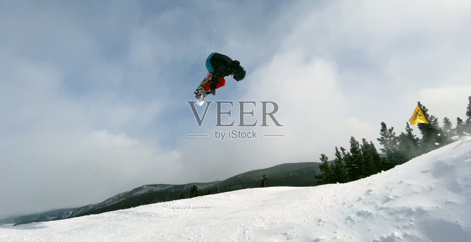 一个滑雪板在完整的冬季装备试图在一个滑雪板在博尔德附近的埃尔多拉滑雪度假村上跳跃的把戏，科罗拉多州在一个明亮，阳光明媚的冬日照片摄影图片