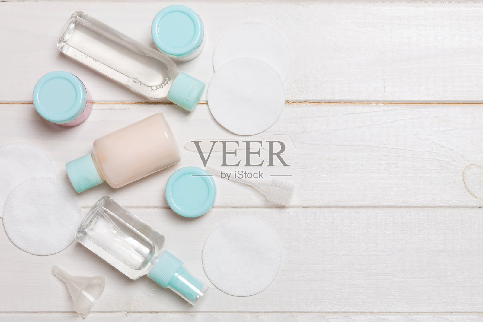 在木制背景上旅行的一组小瓶子。为你的想法复制空间。平铺化妆品成分。顶部视图的奶油容器与棉垫照片摄影图片