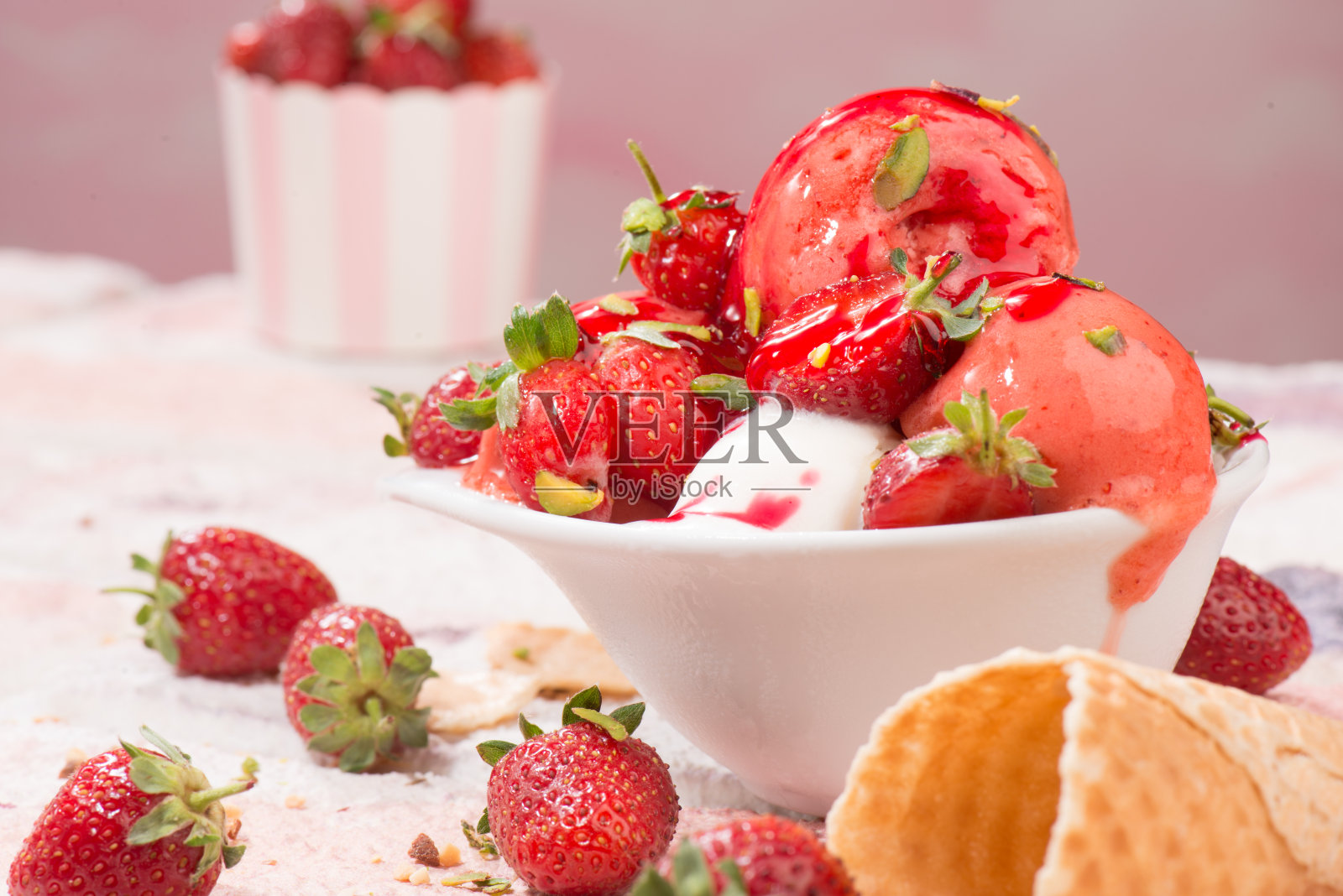 草莓冰淇淋在粉红色背景的杯盘里照片摄影图片