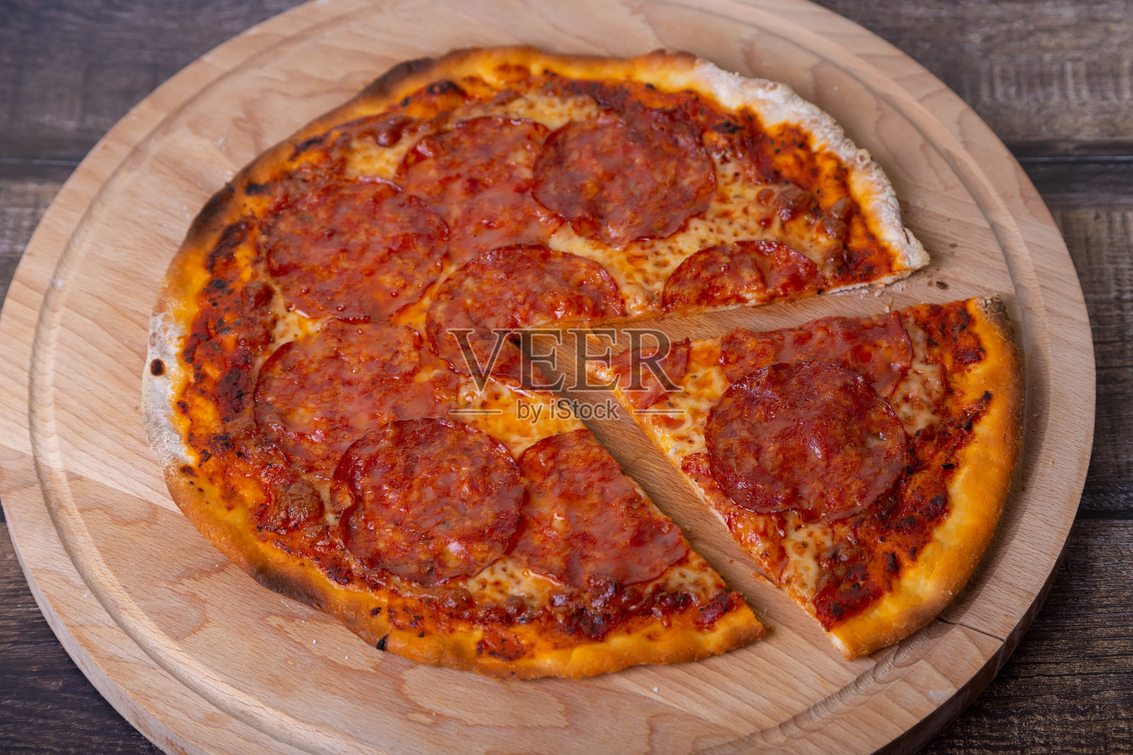 披萨和香肠放在木板上。整块的披萨，切下一块。照片摄影图片