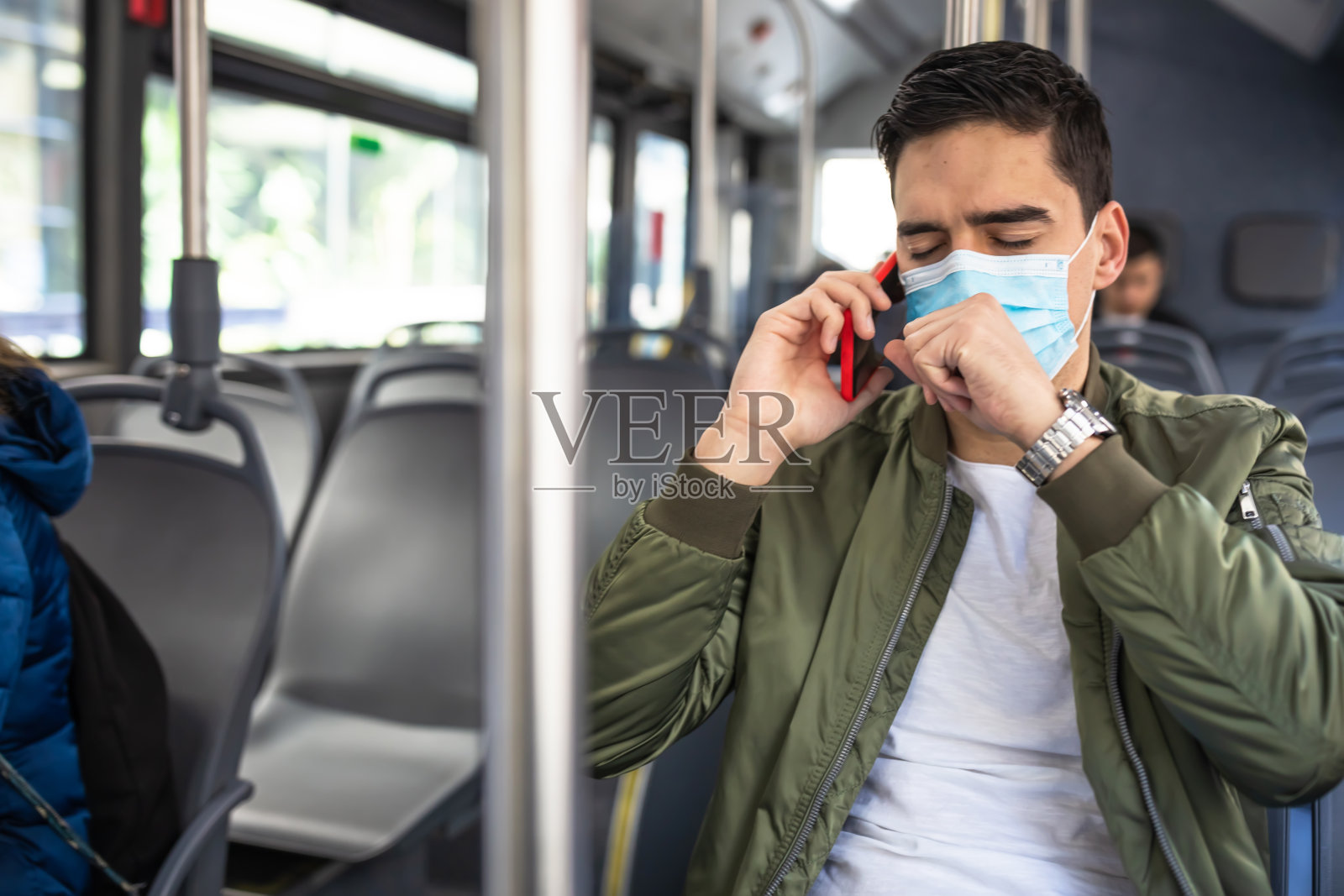 一名男子戴着医用口罩在公共汽车上打电话照片摄影图片