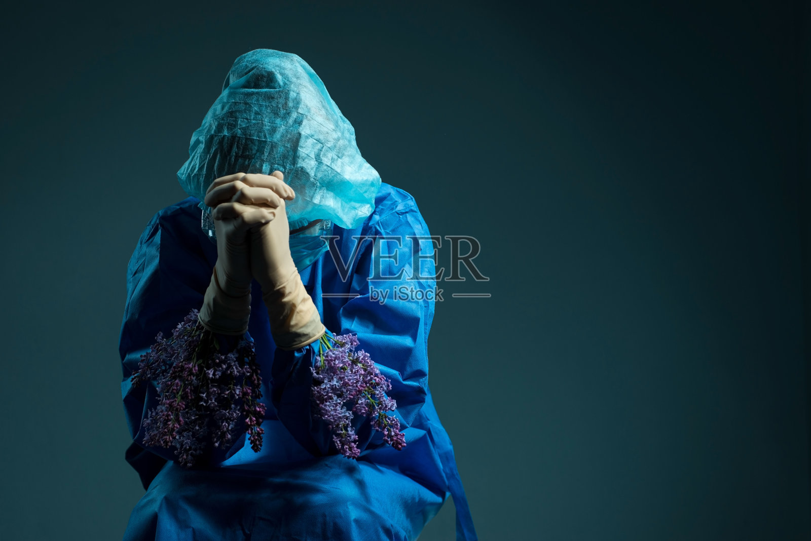 丁香花从护士手套下长出。医疗概念。医生在无菌手套和蓝色工作服中拿着黄色的花朵。健康和医疗。手术照片摄影图片