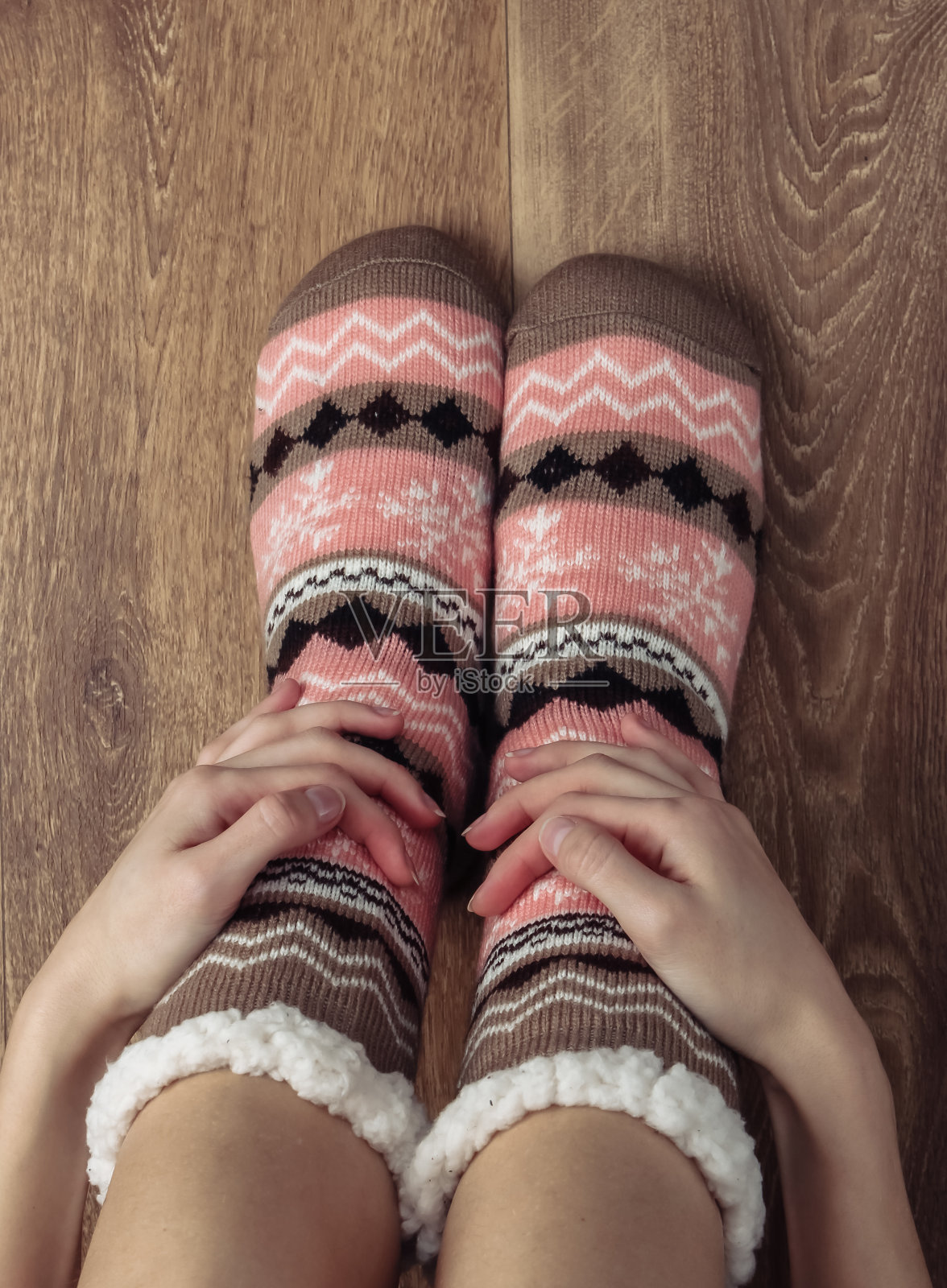 女人的腿在温暖舒适的袜子在房间的木地板上。照片摄影图片