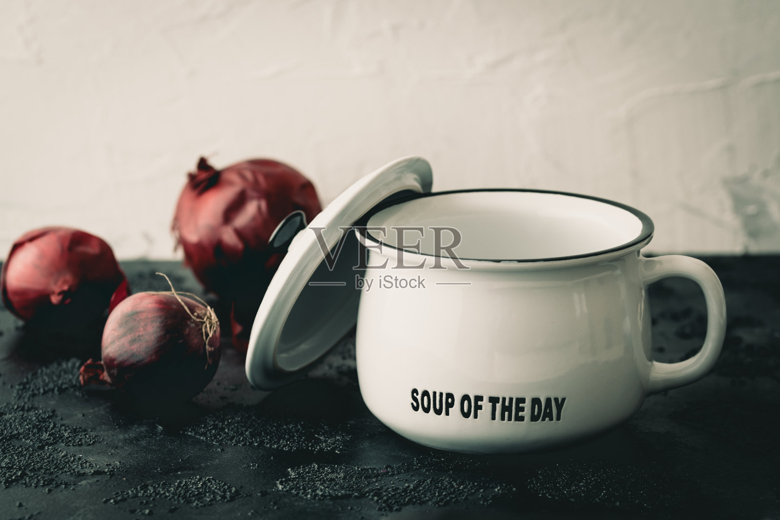 白色的碗和盖子，汤的日子字母和红洋葱在黑白的背景照片摄影图片