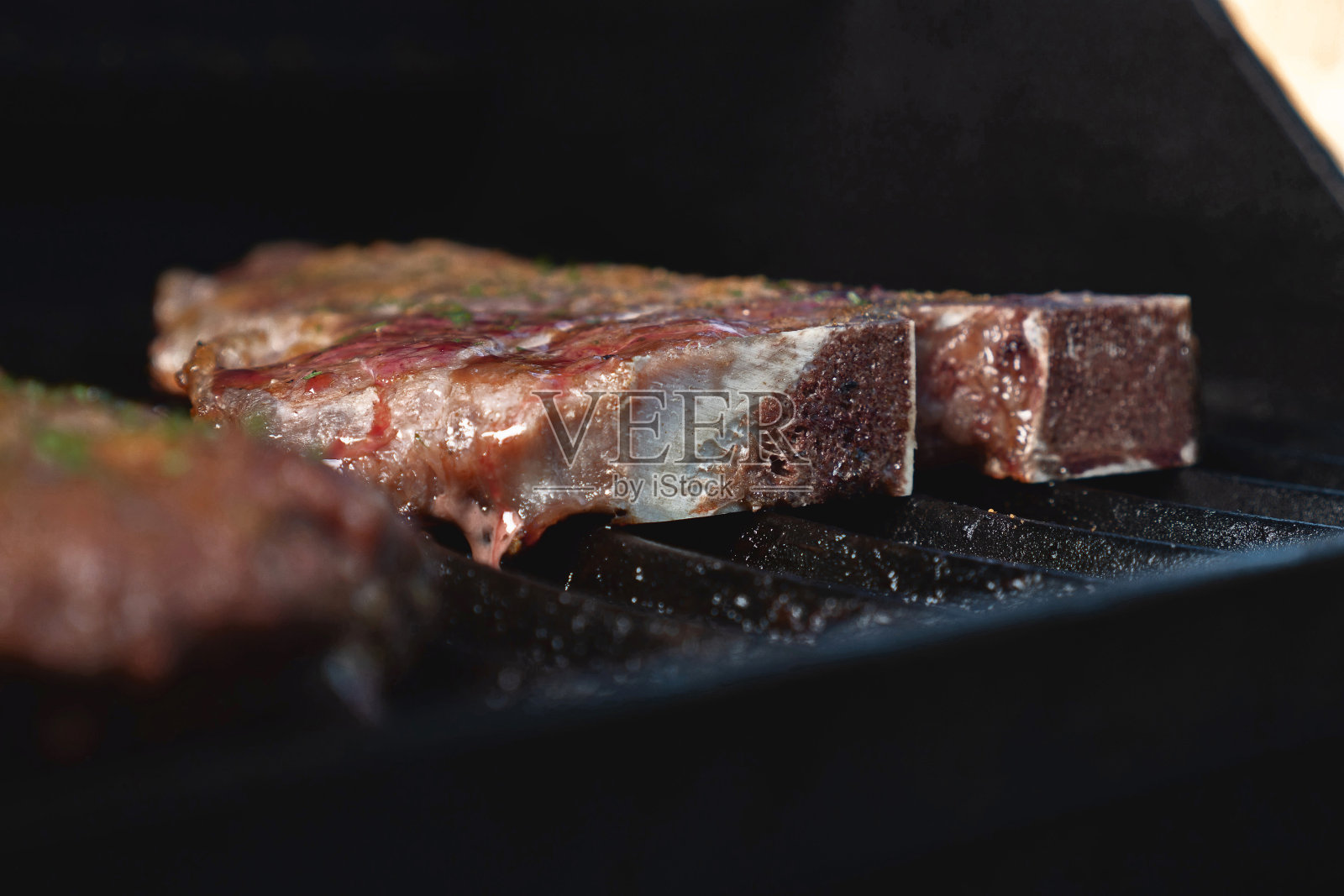 热烤架上的t骨牛排与木炭和火焰照片摄影图片