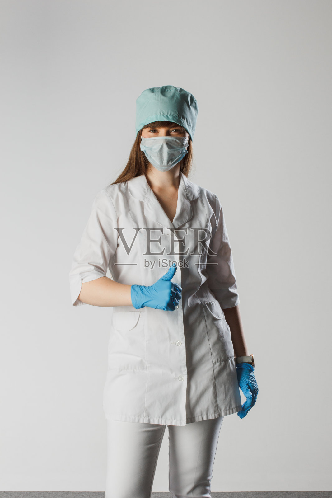 年轻的女护士在孤立的背景显示手势批准显示拇指向上的符号和形状的手。医学概念。照片摄影图片