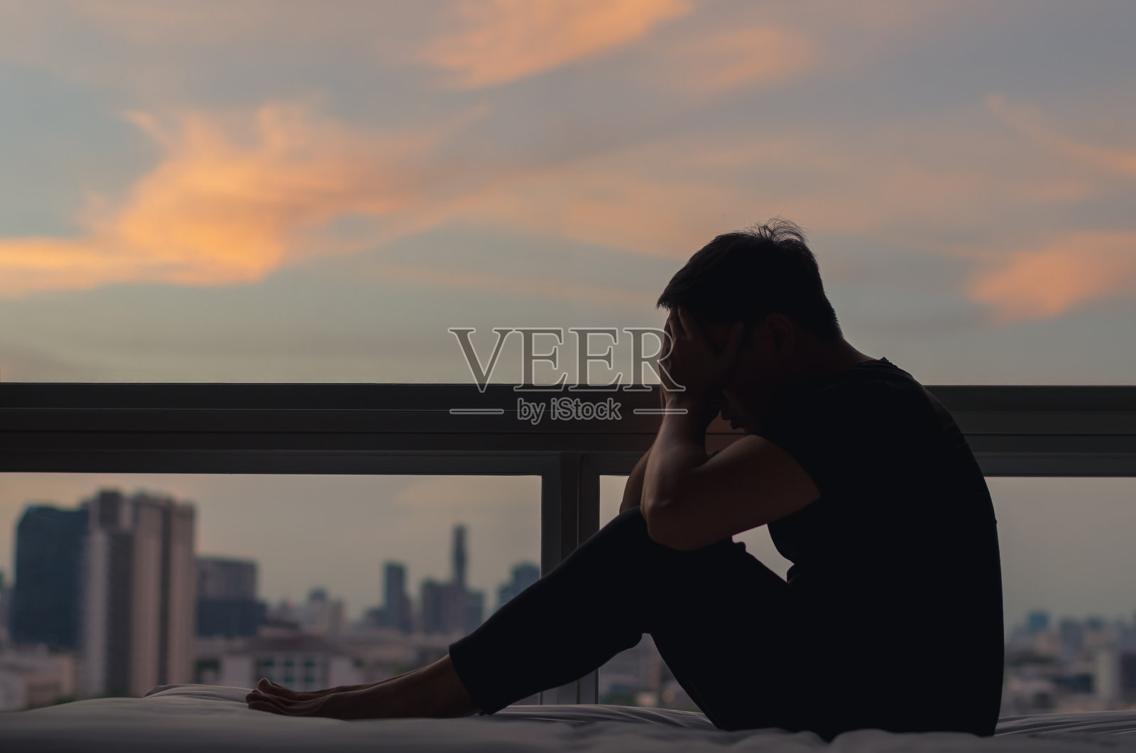 一个人坐在床上，感到沮丧照片摄影图片