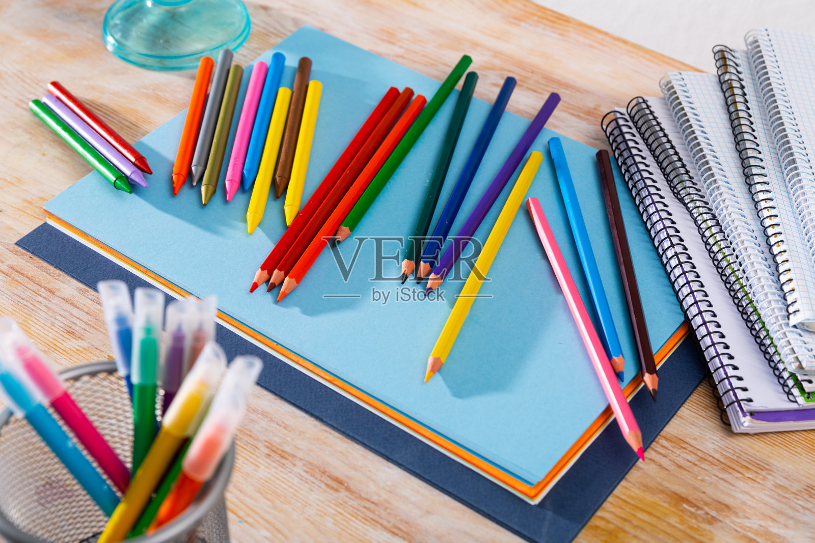 桌上放着五颜六色的铅笔、纸和笔记本照片摄影图片