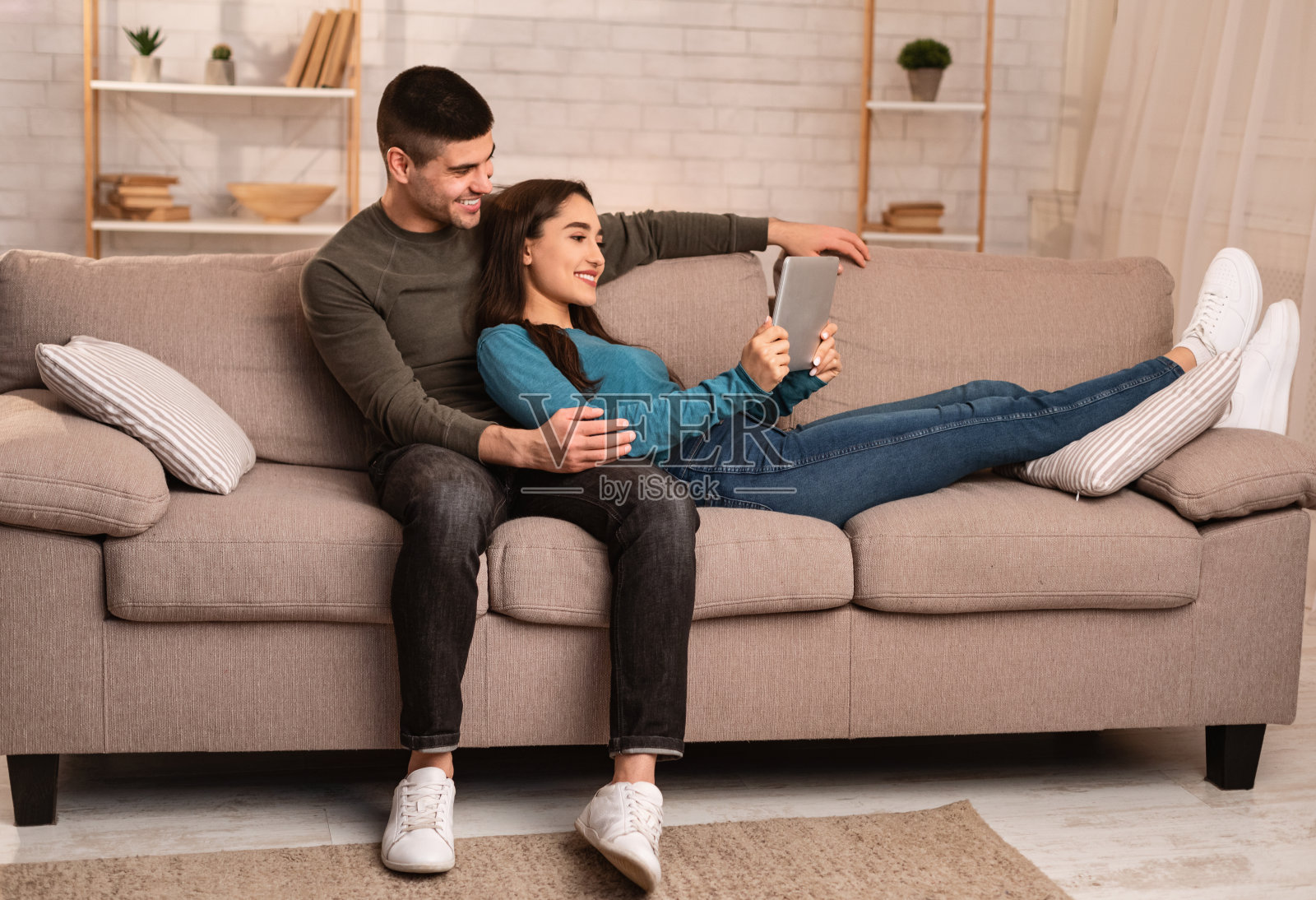 一对情侣躺在沙发上，用着平板电脑照片摄影图片