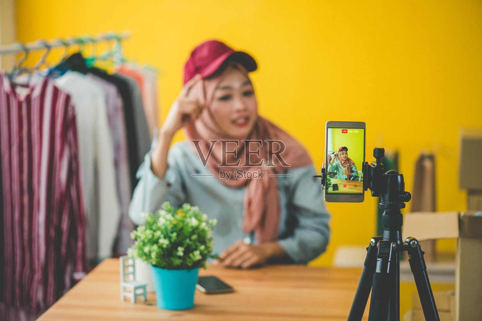 年轻的穆斯林妇女戴着头巾在家在线服装店直播照片摄影图片