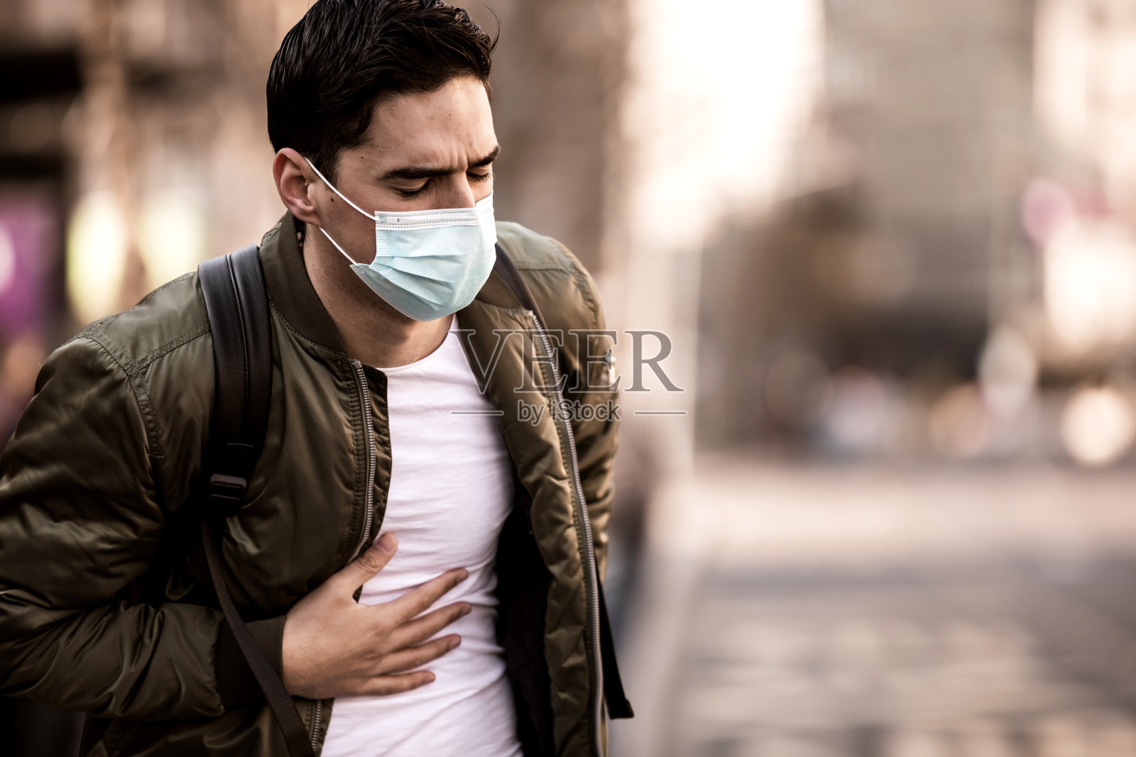 患咳嗽的男子戴口罩保护，因城市建筑空气污染戴口罩，生病的男子戴医用口罩;概念污染，粉尘过敏照片摄影图片