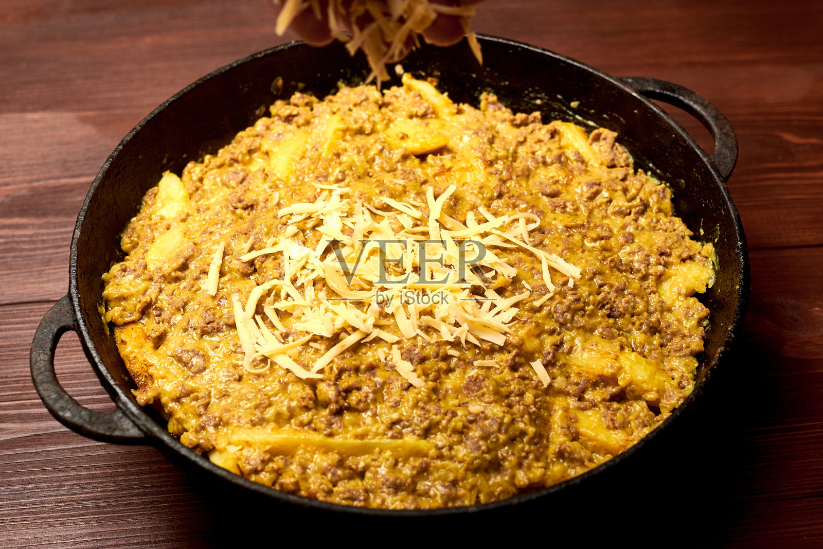 用平底锅煮土豆、肉末和奶酪。照片摄影图片